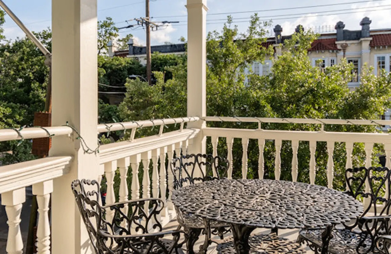 Ornate metal patio table and chairs on white balcony with urban background