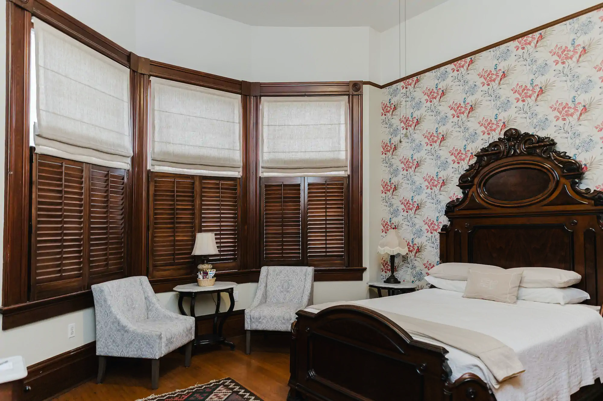  Mint green Victorian mansion with white columns, wraparound porch, manicured lawn and decorative black iron fence entrance 